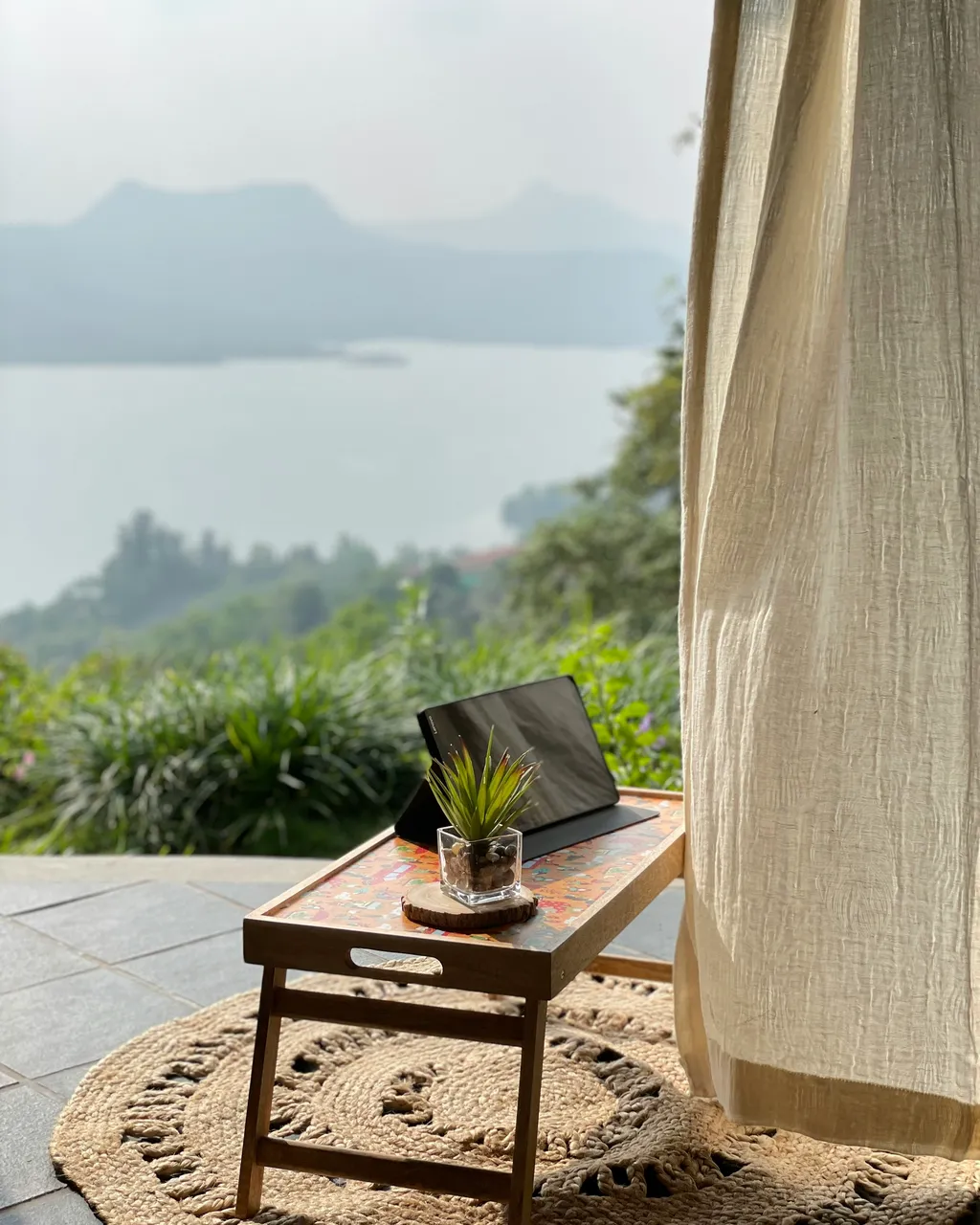 A laptop open on a private terrace overlooking a misty valley